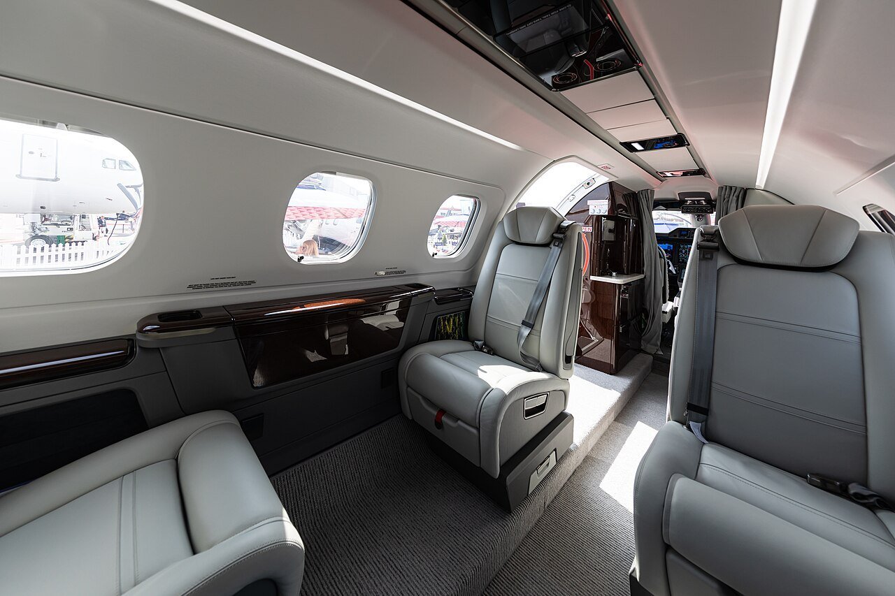 Grey seating and the overhead technology panel inside a Phenom 300E displayed at EBACE 2019.