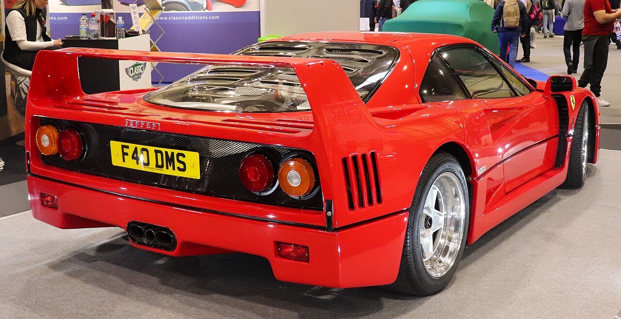 Red Ferrari F40 road coupe viewed from behind, showing its fixed wing and vented engine cover.