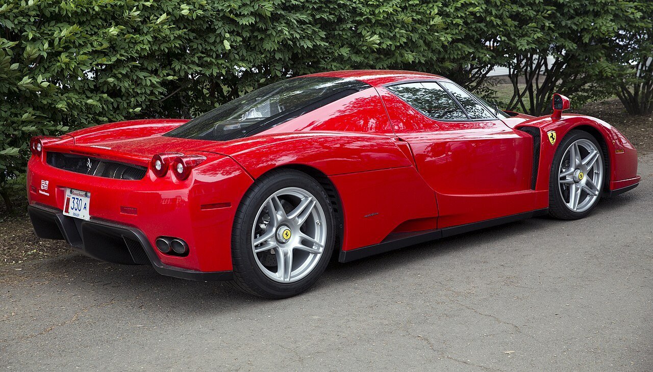 Red Ferrari Enzo road coupe viewed from the rear right, showing its diffuser and round taillights.